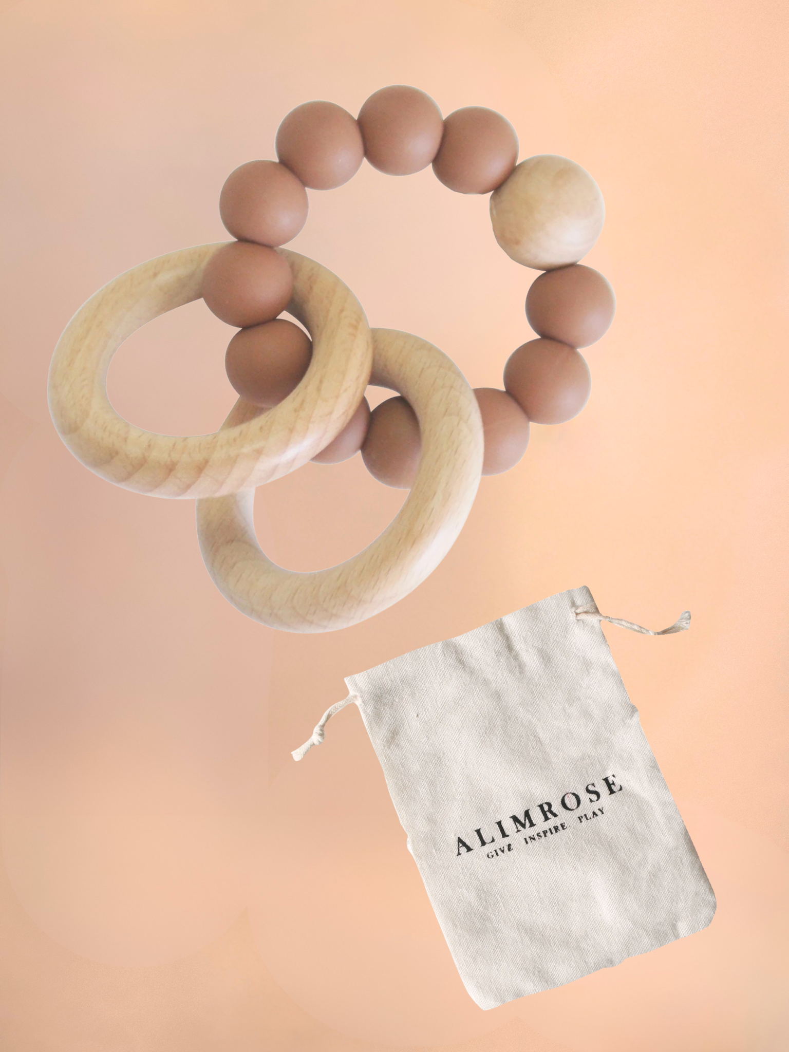 Wooden baby teething rings with a branded pouch on a peach background