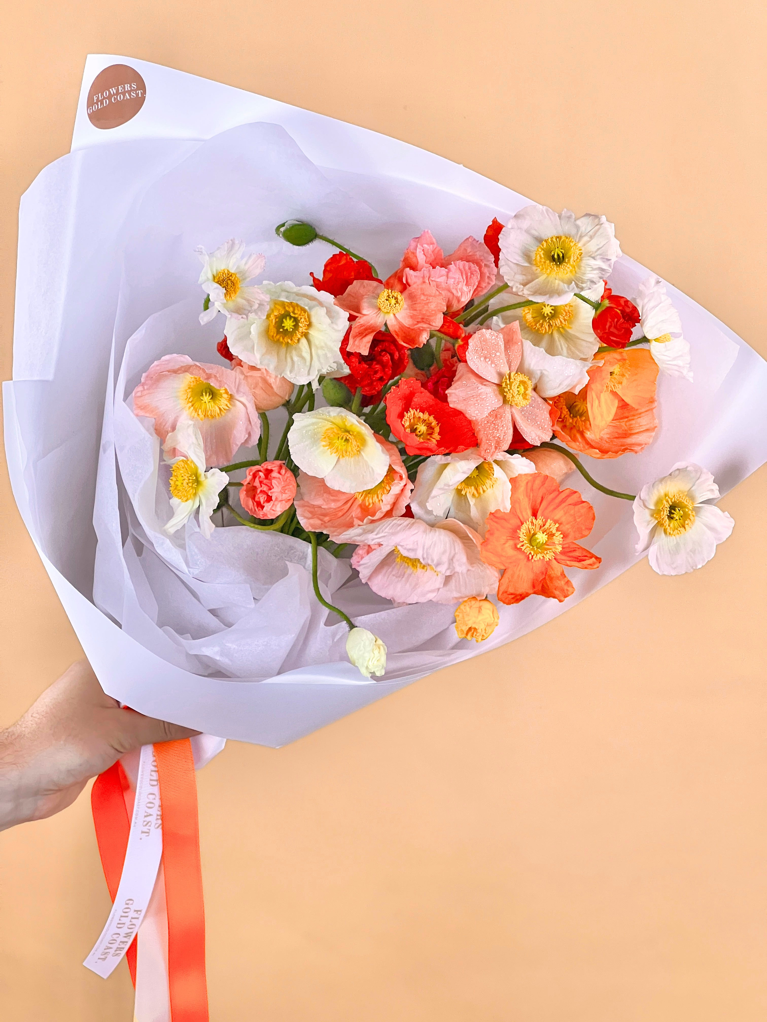 Bouquet of colorful Poppies wrapped in white paper on a beige background